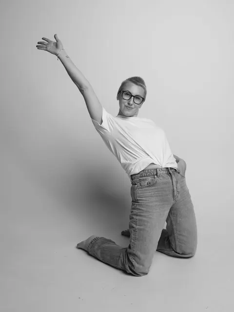 Катерина стоїть на одному коліні й тягне руку вгору